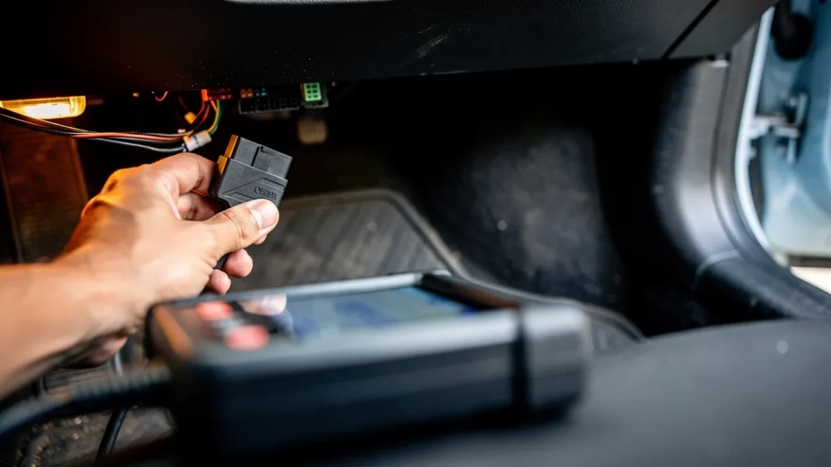 une valise de diagnostic obd2 branchee sous le volant d une voiture Une valise de diagnostic OBD2 branchée sous le volant d'une voiture.